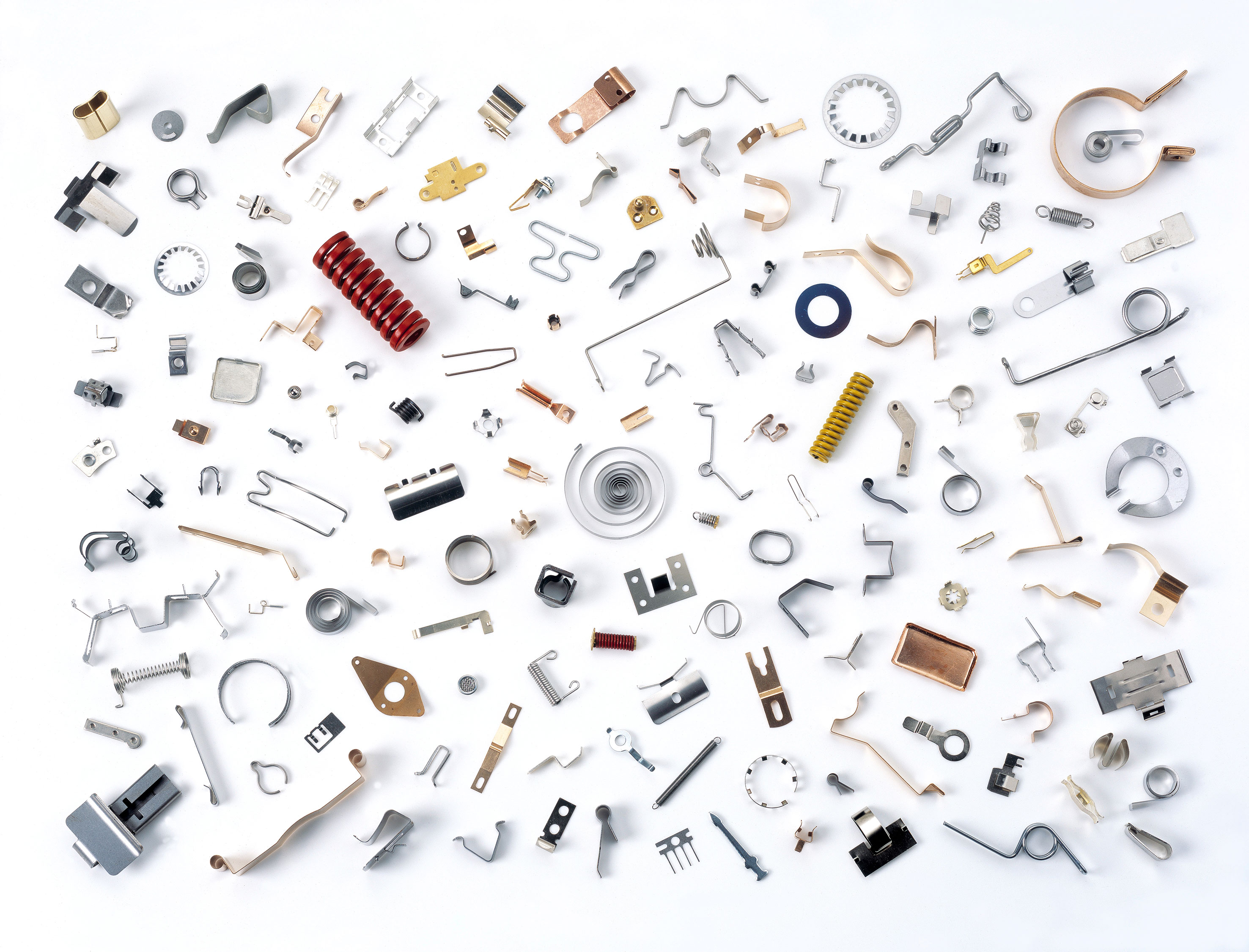 Una collezione diversificata di molle metalliche, clip e componenti realizzati con precisione in diverse forme, dimensioni e finiture, disposte con cura su uno sfondo bianco pulito per valorizzare varietà e qualità artigianale.